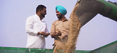 two Rice Farmers in India talking next to farm equipment